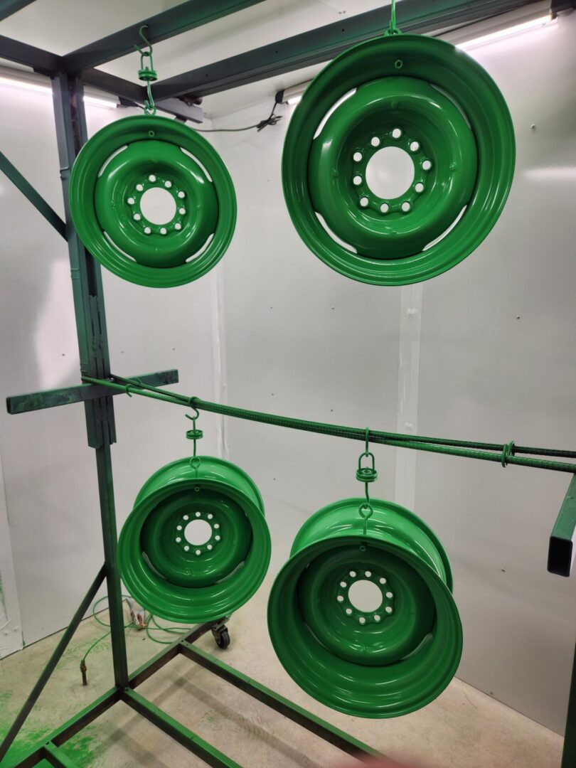 A group of green wheels hanging from a metal pole.