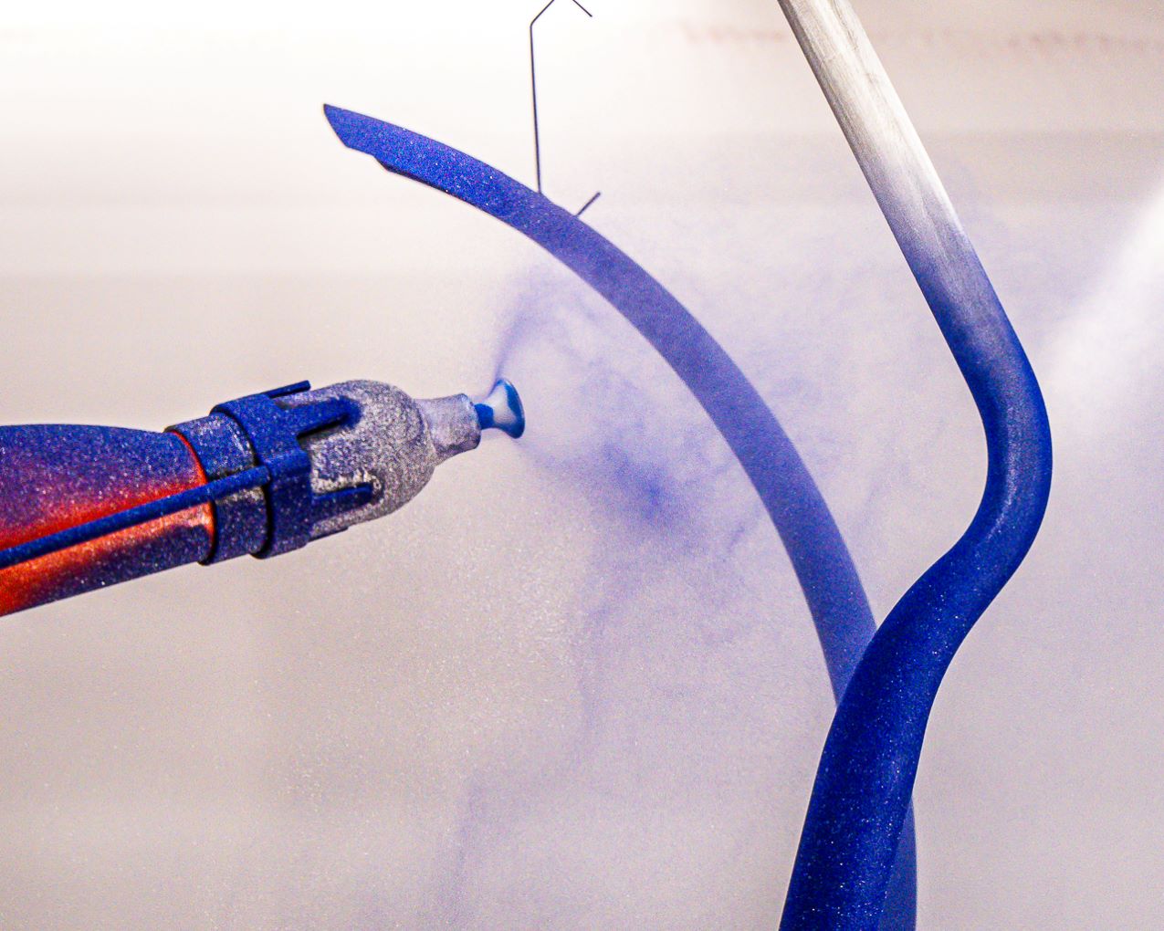 A person spraying blue paint on the wall.